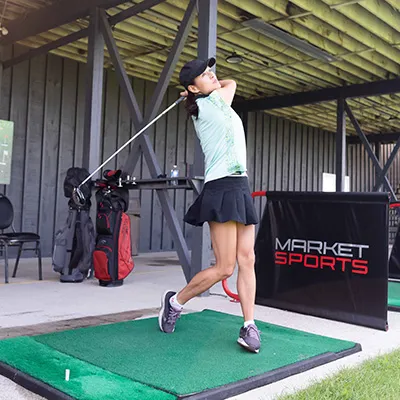 A woman drives a golf ball at the Market Sports driving range.
