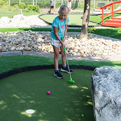 A young girl putts a ball on a Market Sports mini golf course.